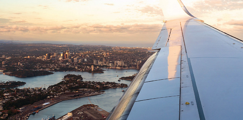 View of a person looking out of an airplane window overlooking a city.