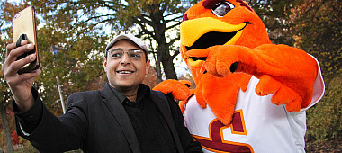 Man takes a selfie with the SU Mascot Benny The Hawk