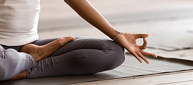 Yogi black woman practicing yoga lesson, breathing, meditating, doing Ardha Padmasana exercise, Half Lotus pose with mudra gesture, worki...