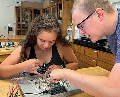 Carl Faust, chair and associate professor of physics, assists Hannah Needham '23 in the lab.