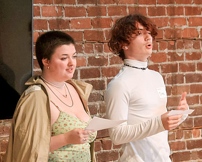 Student researchers Caelie Bratcher '25, left, and Landon Dino Haynes '27, right, speak while standing in front of a brick wall.