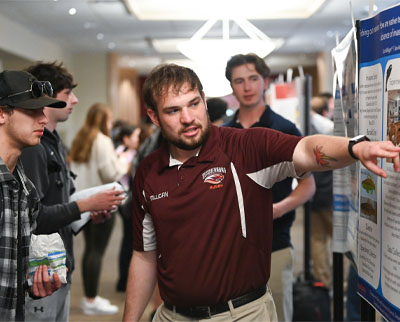 Scott Milligan explains his poster to an onlooking student.