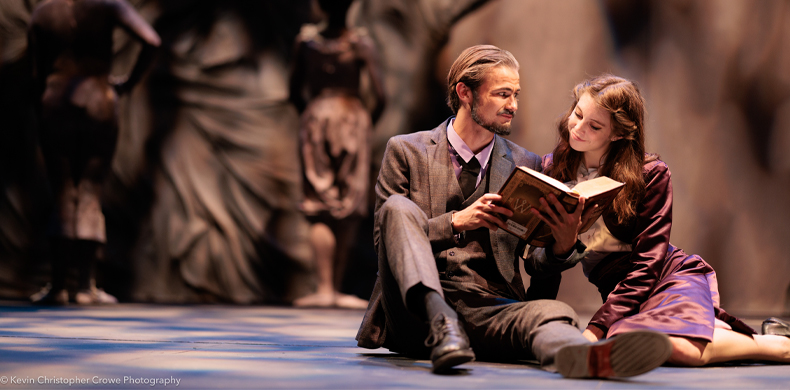 A man and woman sit closely in the foreground looking at a book, while two figures lurk in the background.