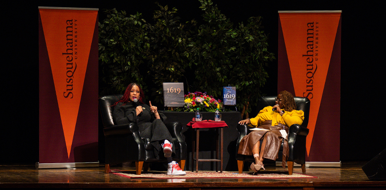 Nikole Hannah-Jones, left, and Stacey Pearson-Wharton, dean of health & wellness at Susquehanna University, right, seated on a stage.