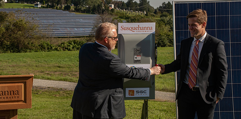 Susquehanna University President Jonathan D. Green, left, and Richard Walsh, program lead, clean energy solutions, WGL Energy, flip the s...
